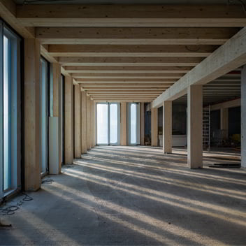 Building under construction with exposed timber structures and large windows.