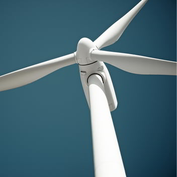 Wind turbine viewed from below against a blue sky.