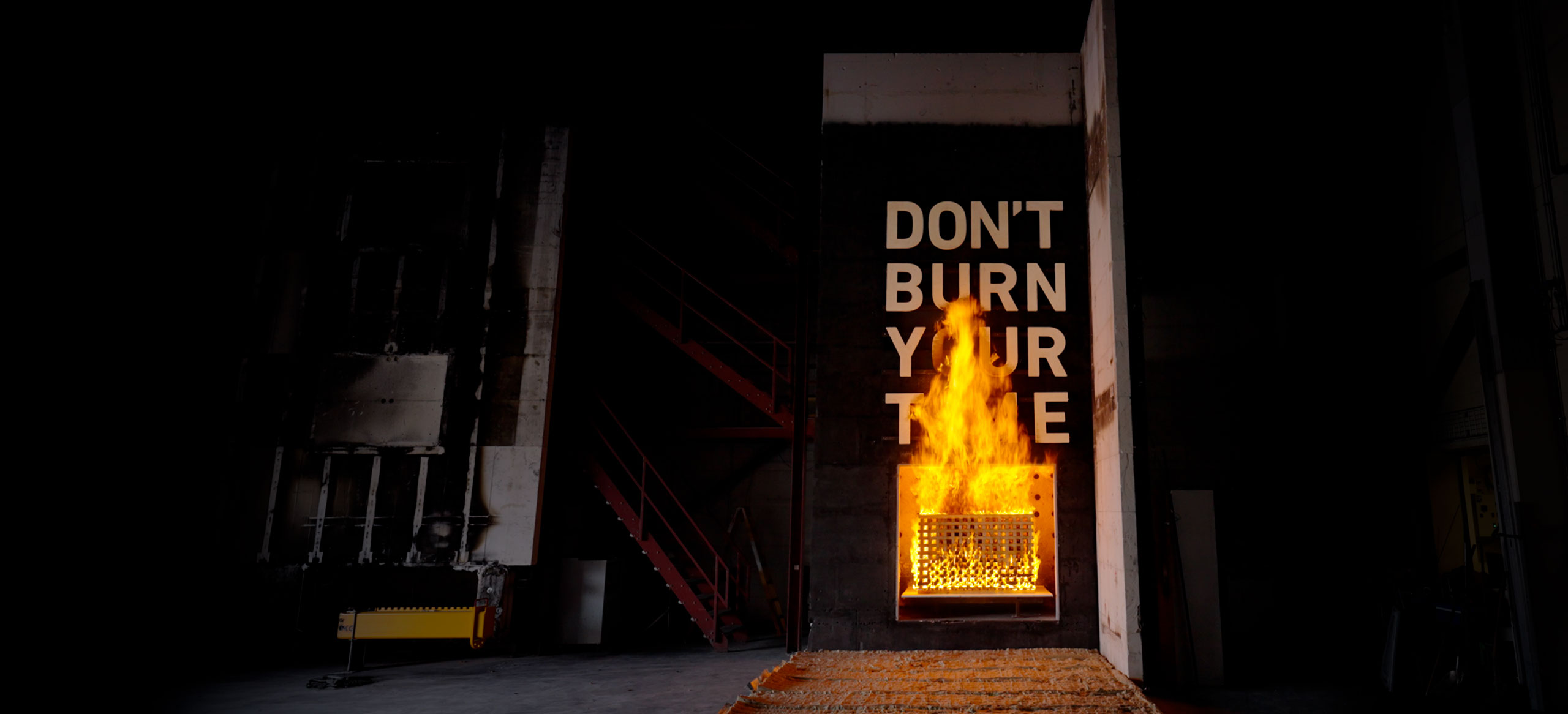 Fire test with intense flames and the text ‘Don’t burn your time’ in DBI’s test hall.