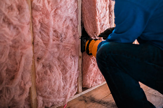 Worker installing insulation material in a wall construction.