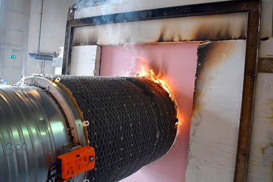 Fire test of an insulated ventilation duct with flames around a wall penetration.