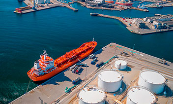 Port with vessel and fuel storage tanks, illustrating maritime resilience, port safety and the green transition in shipping and transport infrastructure.