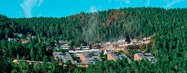 Smoke rising from Krokstadelva in Norway after a major fire, illustrating rapid fire spread in hillside timber housing, forest terrain and emergency response.