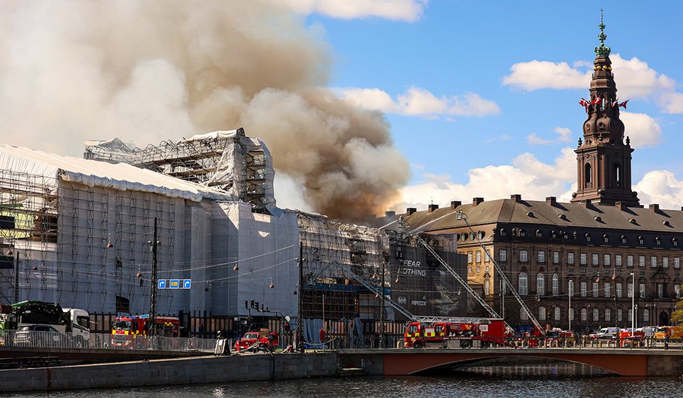 Fire at the historic Børsen building in Copenhagen during renovation, with heavy smoke rising from the scaffold-covered structure while fire crews respond at the scene.