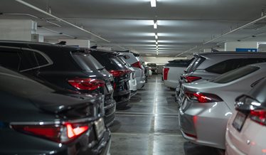 Closely parked cars inside an indoor car park with a low ceiling.